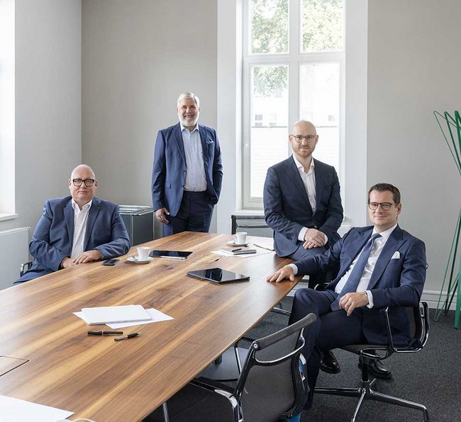 Partner sitzen gemeinsam am Besprechungstisch und lächeln in die Kamera