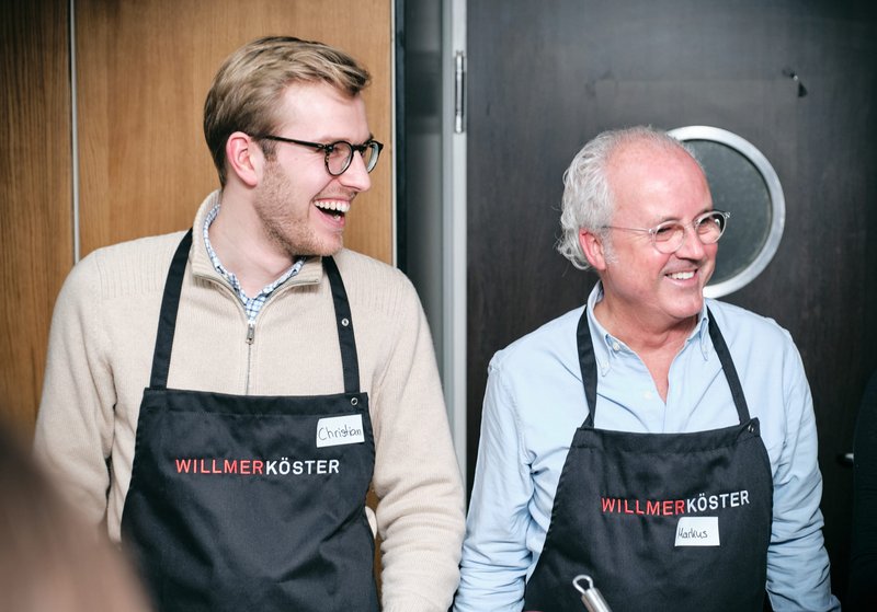 Impressionen vom gemeinsamen Kochen bei der Weihnachtsfeier der Kanzlei – Zwei Mitarbeiter lachen